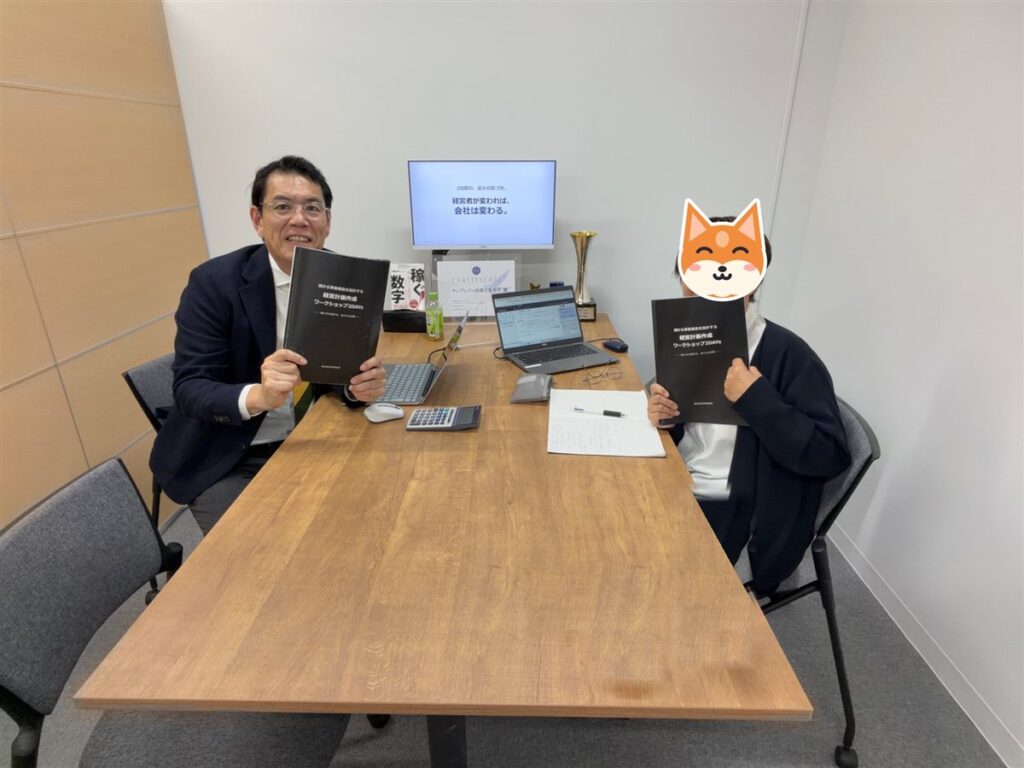 経営計画作成ワークショップ2DAYsのテキストを持つ社長と馬醫光明